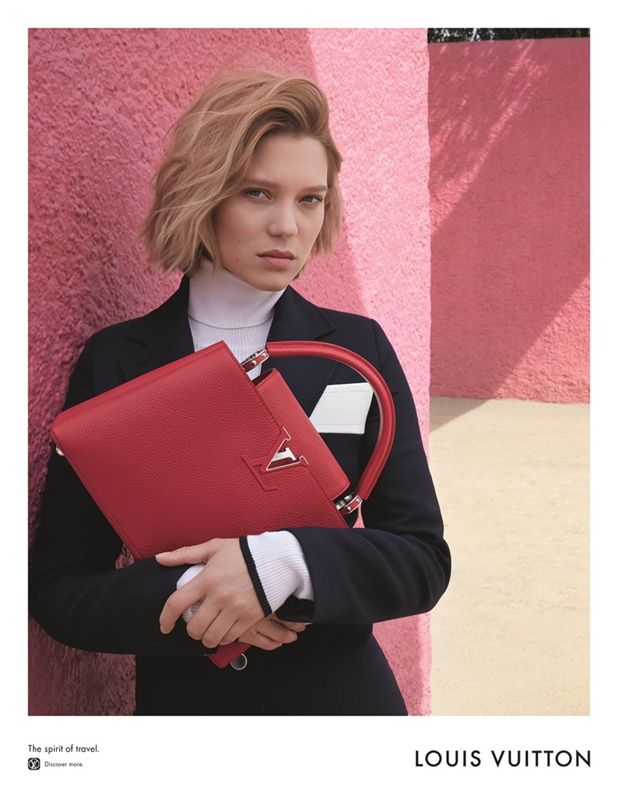 Młoda dziewczyna, ubrana w golf, trzyma czerwoną torbę marki Louis Vuitton