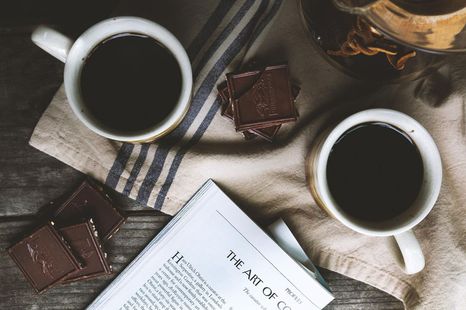 Dwie filiżanki kawy, książka, obrus i czekolada