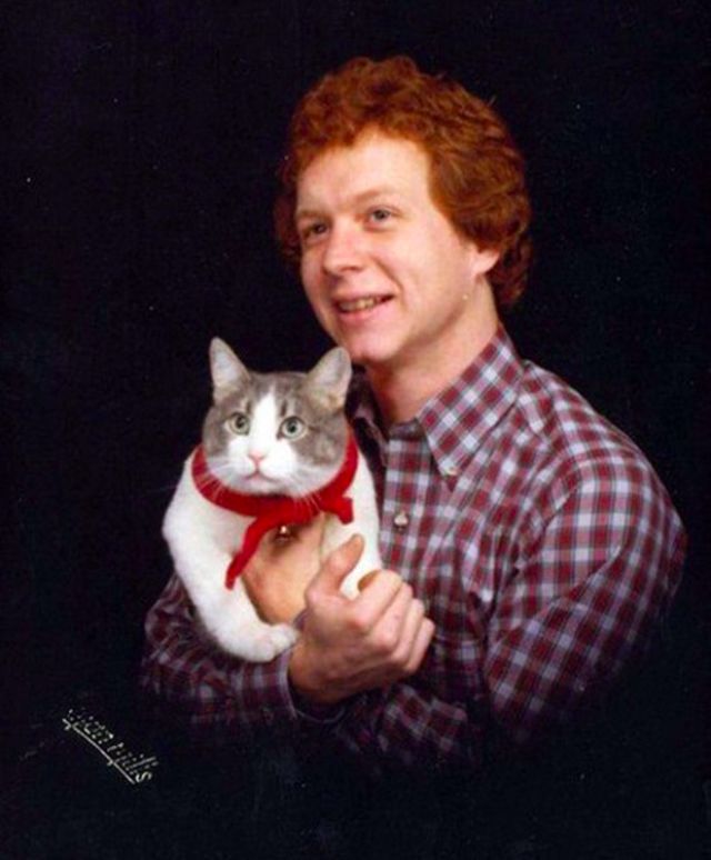 Mężczyzna w koszuli w kratę trzyma na rękach kota