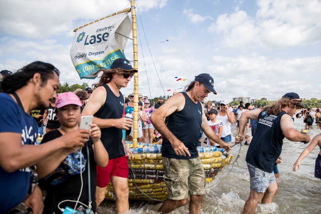 Ludzie stojący w otoczeniu łódek z puszek po piwie