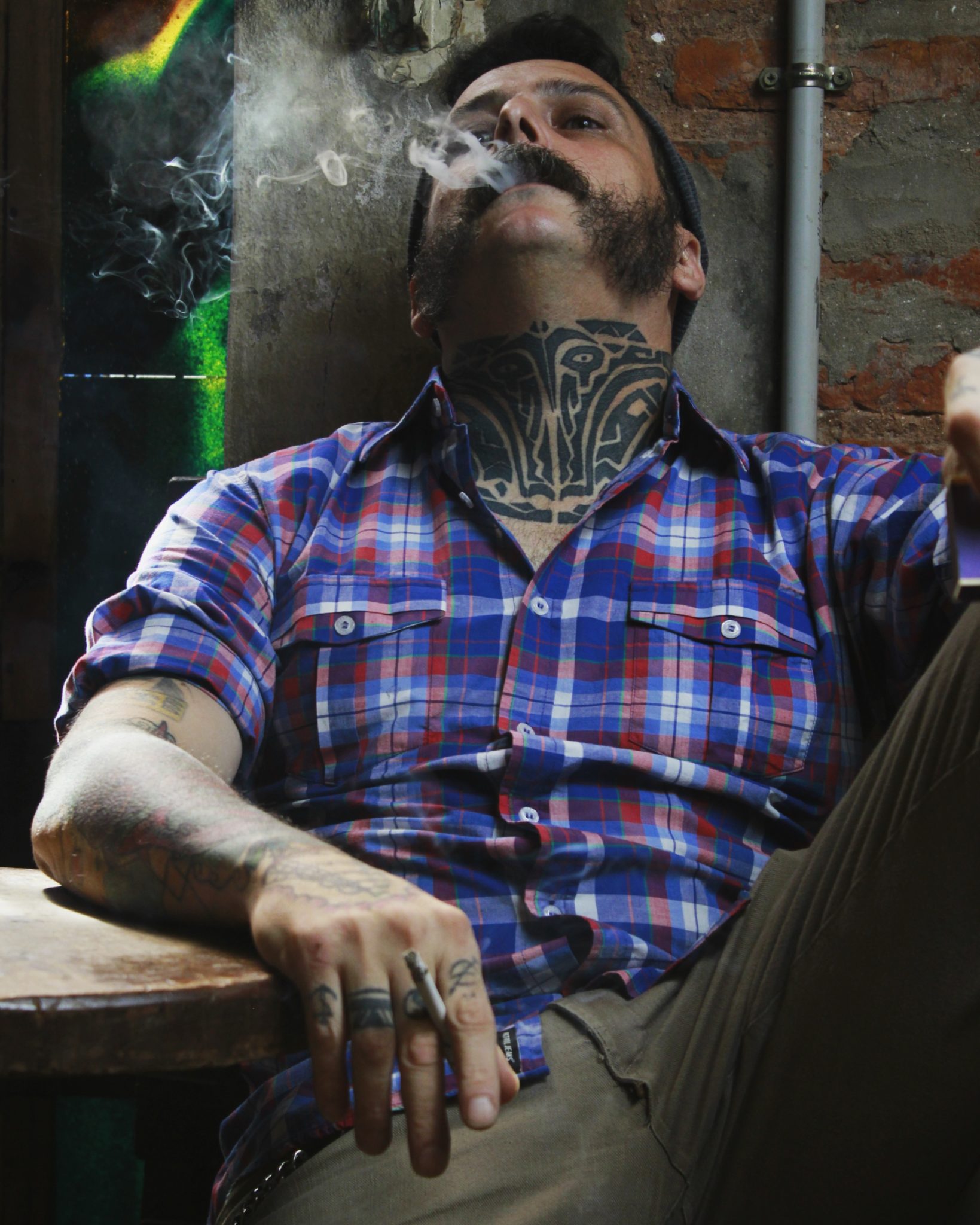 Gość w koszuli, palący papierosa i siedzący na fotelu