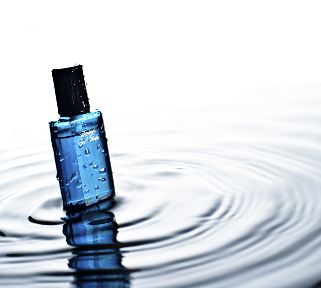 Niebieska butelka perfum zanurzona w wodzie