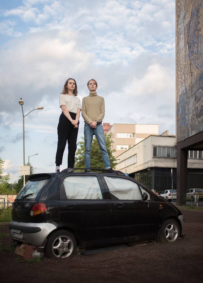 Chłopak i dziewczyna stojący na dachu samochodu
