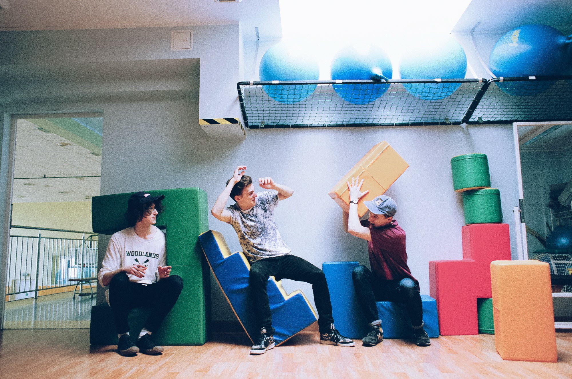 Trzech chłopakow w pokoju zabaw rzucaja sie kolorowymi kwadratami