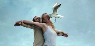 Kobieta i mężczyzna stojący na dziobie statku i ptak wlatujący w twarz kobiety