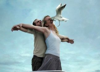 Kobieta i mężczyzna stojący na dziobie statku i ptak wlatujący w twarz kobiety