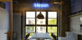 Pomieszczenie z dużym stołem i neonem z napisem MISSION