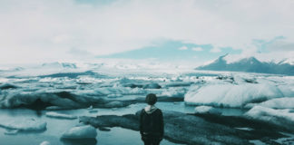 postać stojąca na unoszącej się na wodzie krze lodu