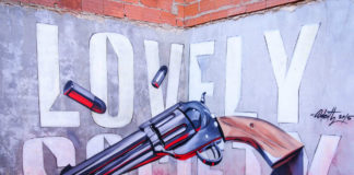 Mural na ścianie przedstawiający napis "LOVELY SOCIETY" i rewolwer