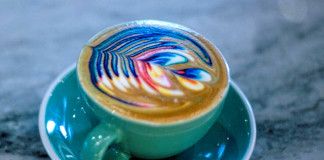 niebieska filiżanka, wypełniona kawą z kolorowym wzorem na wierzchu