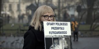 Blondynka w ciemnych płaszczu trzyma transparent z lisem i podpisem "Ofiary polskiego przemysłu futrzarskiego"