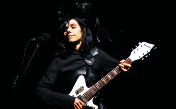 Brunetka z czarnym pióropuszem i białą gitarą