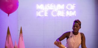 Ciemnoskóra kobieta w jasnej sukience robi lody, za nią napis "Museum of Ice Cream"