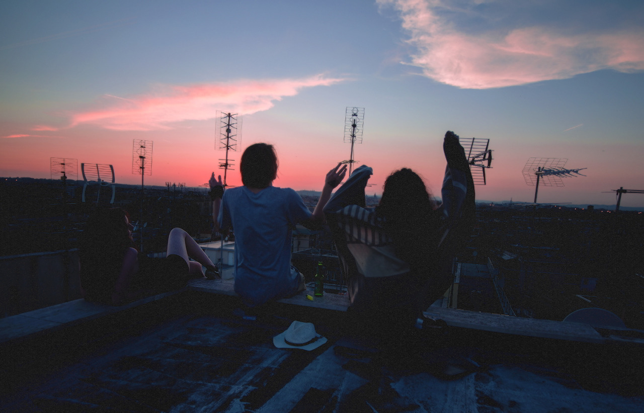 Chłopak i dziewczyna siedzą na dachu i podczas zachodu słońca