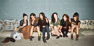 Grupa dziewczyn w streetwearowych ciuchach siedzi na ulicy przy murku