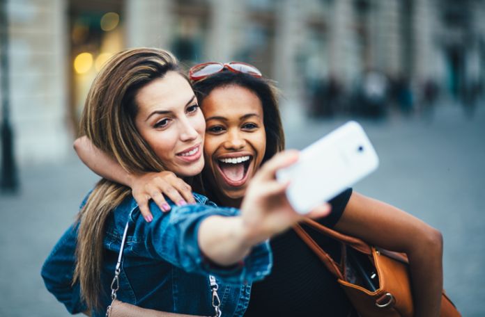 Dwie dziewczyny robią wspólne selfie białym smartfonem