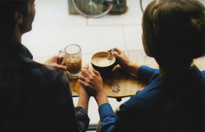 Dwie osoby siedzą tyłem z filiżankami kawy