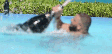 Ciemnoskóry mężczyzna w basenie, trzymający dmuchaną butelkę szampana