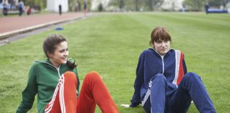 Dwie dziewczyny w sportowych ubraniach siedzą na boisku szkolnym
