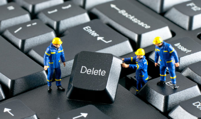 Grupa robotników usuwająca przycisk delete z klawiatury