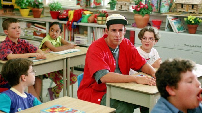 Chłopak w czerwonej koszulce siedzi w szkolnej ławce
