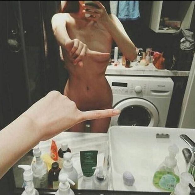 Naga kobieta robi zdjęcie w lustrze zasłaniając się palcem