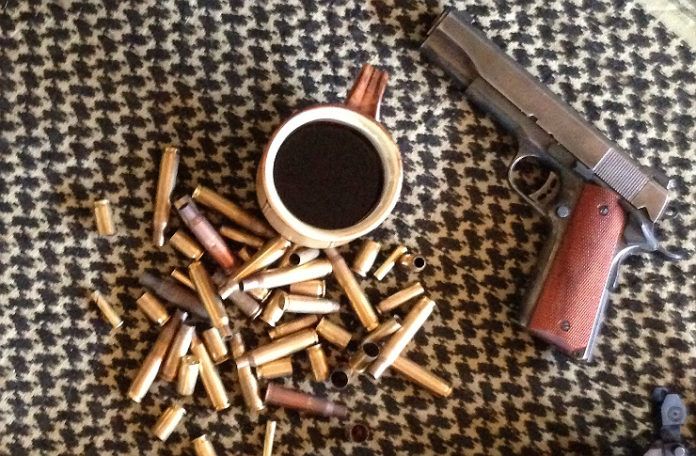 Kubek kawy, obok naboje i pistolet