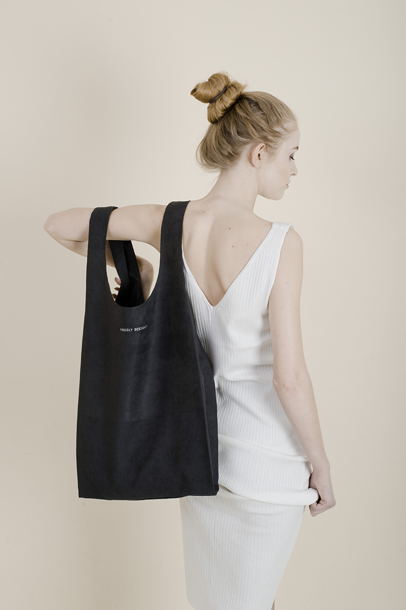 Dziewczyna w jasnej sukience z odkrytymi plecami i ciemną torbą na ramieniu