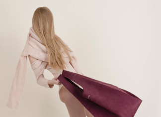 Dziewczyna w różowym narzuconym na ramiona swetrze, machająca bordową torbą
