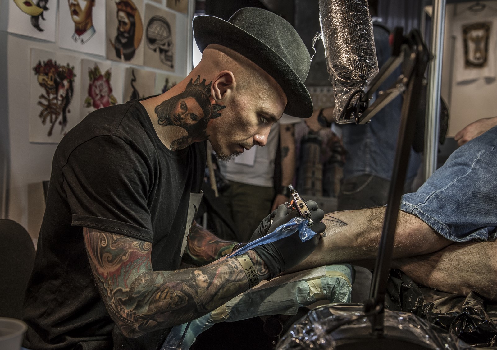 Mężczyzna w tatuażach, tatuujący czyjąś rękę