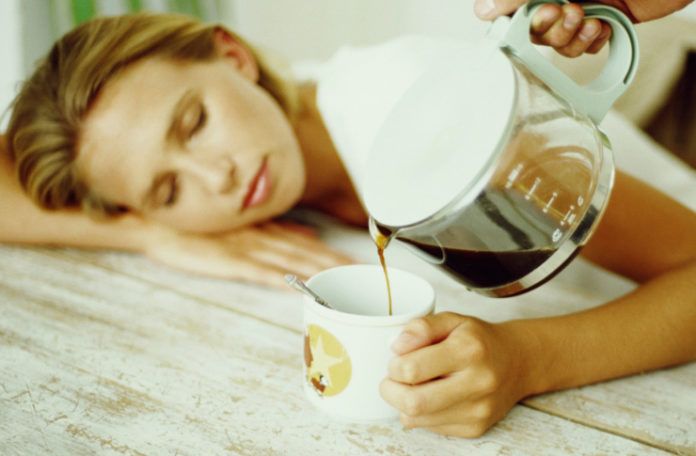 Śpiąca kobieta trzymająca filiżankę, ktoś nalewa do niej kawy