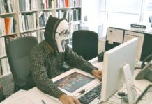 obrazek przestawia osobę siedzącą przed komputerem z założoną na twarz maską