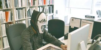 obrazek przestawia osobę siedzącą przed komputerem z założoną na twarz maską