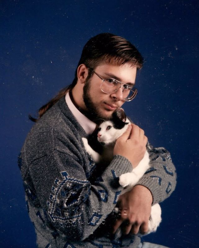 Portret mężczyzny ubranego w nerdowy sweter, przytulający kota