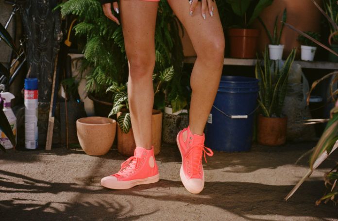 Nogi kobiety ubrane w różowo-czerwone trampki Converse
