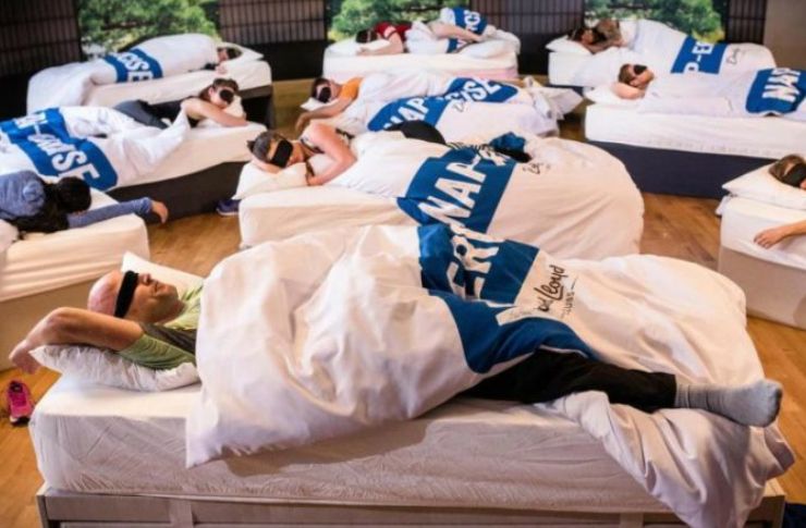 grupa ludzi w opaskach na oczach spiacych w lozkach w bialej poscieli