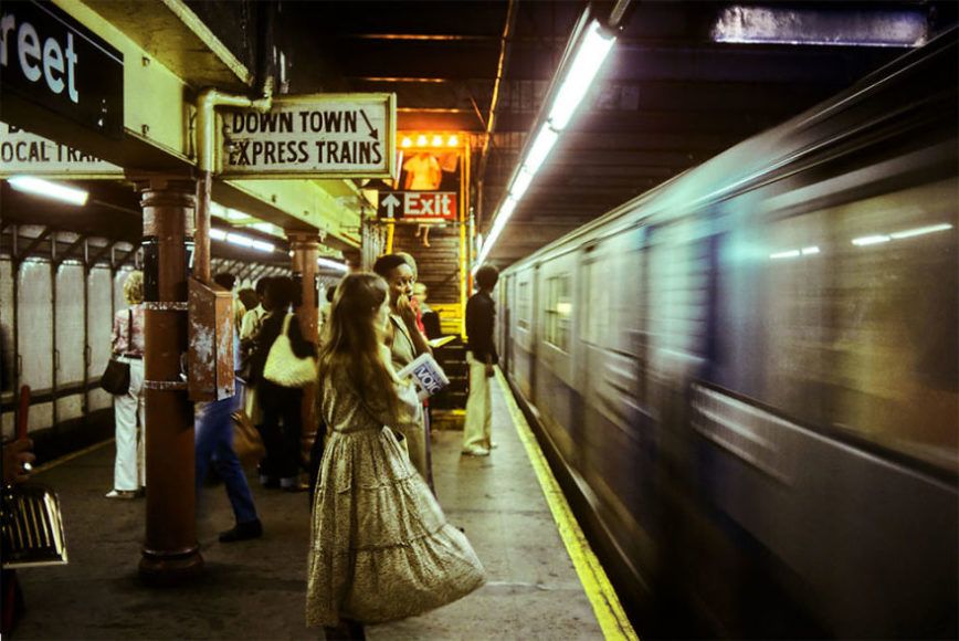 zdjęcie przedstawia pociąg wjeżdżający na stację i ludzi stojących przy krawędzi peronu