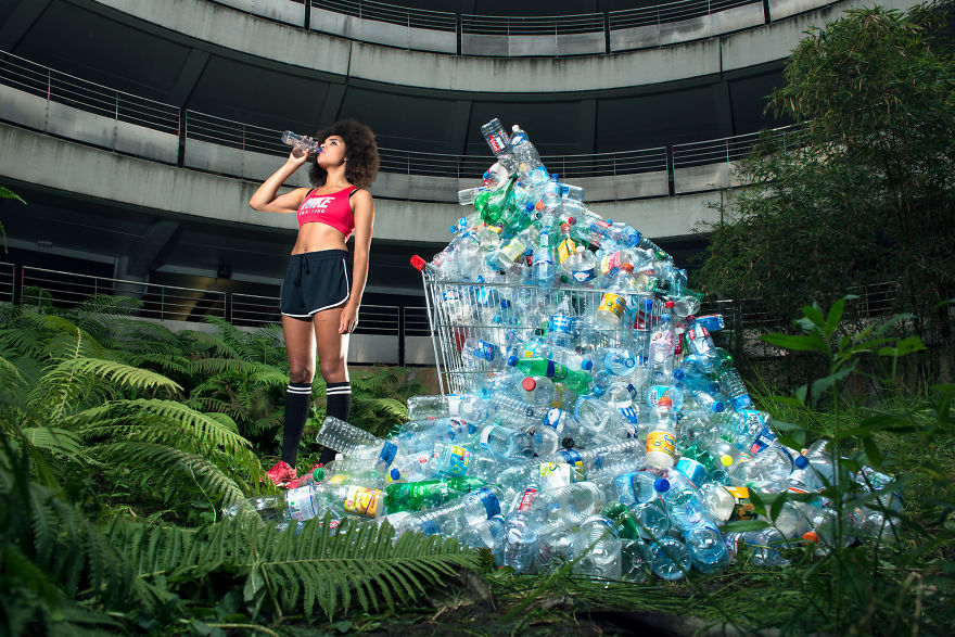 zdjęcie przedstawia dziewczynę pijącą wodę, a obok niej jest duża sterta pustych butelek po wodzie