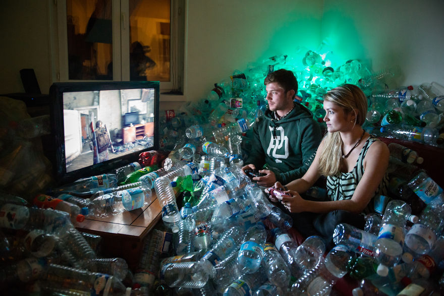 Zdjęcie przedstawia parę grającą na konsoli w otoczeniu sterty pustych butelek