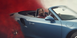 Mężczyzna siedzący w samochodzie za którym unosi się czerwona chmura dymu