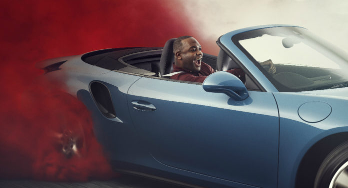 Mężczyzna siedzący w samochodzie za którym unosi się czerwona chmura dymu