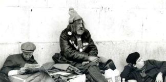 Czarno-białe zdjęcie przedstawiające troje bezdomnych mężczyzn