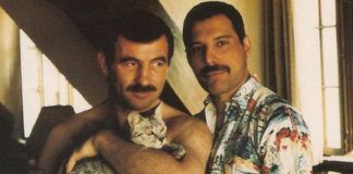 na zdjęciu są dwaj mężczyźni pozujący do zdjęcia, jeden trzyma kota na rękach
