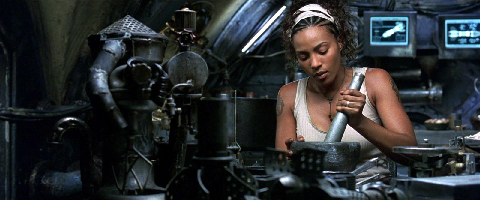 Zdjęcie czarnoskórej kobiety z hutą na splatającą włosy siedzi przy maszynie i konstruuje.