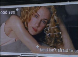 Plakat przedstawiający kobietę z kręconymi włosami i dorysowany obok penis