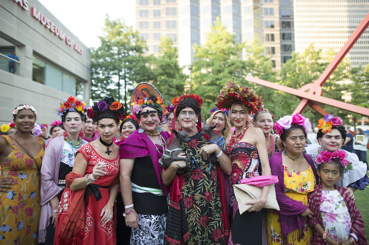 Cieszący się ludzie przebrani za Fridę Kahlo - z wiankami na głowach i różowymi chustami na ramionach