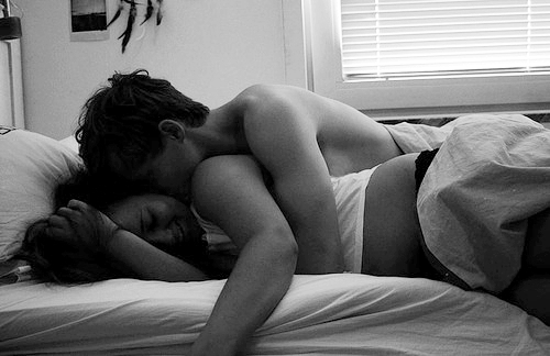 Czarno-białe zdjęcie, na którym para w białej bieliźnie leży na łóżku