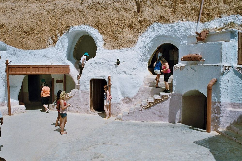 Grupa turystow, ktora zwiedza tunezyjskie miasteczko Matmata, w ktorym krecono Star Warsy. Widac ludzi wchodzących i wychodzacych z tamtejszych tuneli