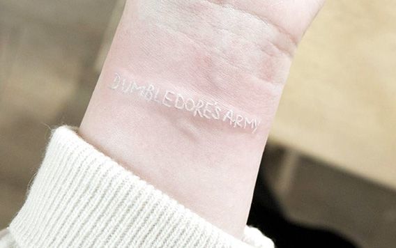 Tatuaż na nadgarsku wykonany białym tuszem, napis "Armia Dumbledore'a"