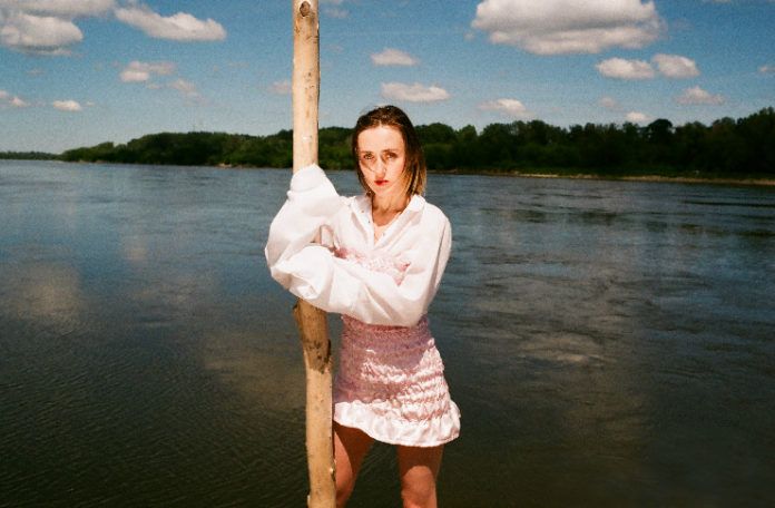 Dziewczyna w różowej spódnicy i białej bluzce stojąca nad brzegiem wody